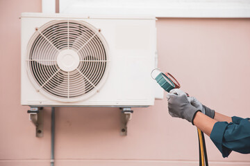 Mechanic air conditioner technician using manifold gauge checking refrigerant for filling home air...