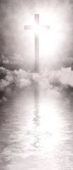 The holy cross of Jesus Christ, reflected in the calm waterside, is a contemplative image that...