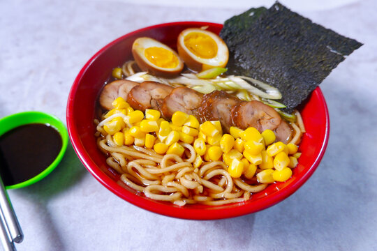 a bowl of shoyu sauce ramen with corn filling, chasu chicken, boiled eggs and leeks Bowl of mouth watering japanese ramen for single serving. Asian noodle soup. close up, selective focus.