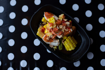 Thai papaya salad or Som Tum add salted eggs and yellow corn on a black background white polka dots