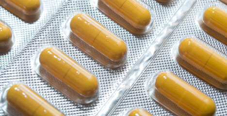 yellow capsules pills pills in a silver blister close-up - obrazy, fototapety, plakaty