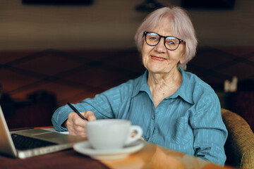 Portrait of an elderly woman in a cafe a cup of drink laptop Social networks unaltered