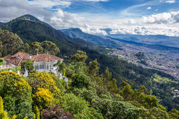 Fototapeta premium View of Monserrate, a high Mountain dominating the city center of Bogota - capital of Colombia, - major tourist attraction and pilgrim destination in a beautiful cloudy day