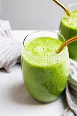 Green Smoothie served in a glass with a straw on a marble table top