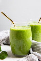 Green Smoothie served in a glass with a straw on a marble table top