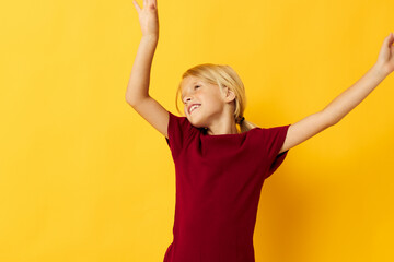 cheerful girl with blond hair gesturing with her hands yellow background