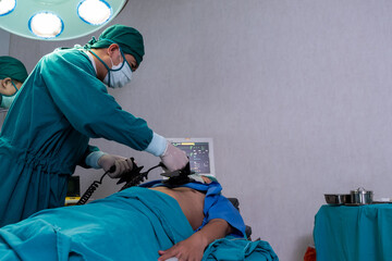 Selective focus at defibrillator while doctor use it to pump at chest of unconscious with low heart rate patient to save life while doing medical surgery inside of operating room. Emergency aid, CPR.