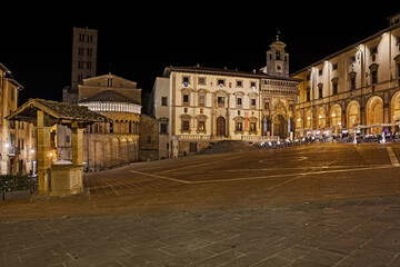 Fototapeta na wymiar Arezzo, Tuscany, Italy: night view of the main square Piazza Grande, with the medieval church and buildings, in the old town of the ancient Italian city of art
