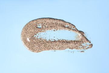 Sample of natural scrub on blue background. Peeling cream with microcapsules. Peach or coffee scrub...