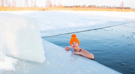 woman swims in a swimsuit in an icy pond. Tempering concept, winter swimming, happy healthy...