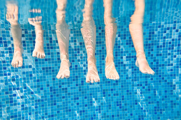 Family legs underwater in swimming pool, mother swim with children under water funny concept, sport...