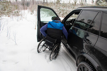 disabled man, spine injury, wheelchair of a person in winter next to his car, wheelchair user difficulties of movement