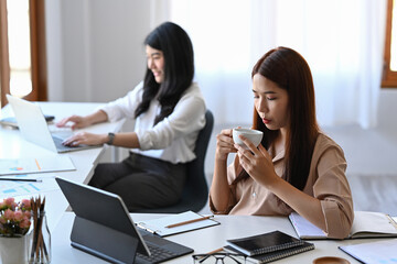 Young businesswoman drinking coffee in the morning at her office desk.