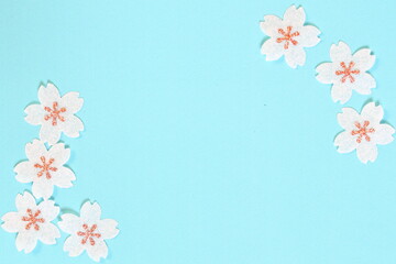 Cherry blossom petals paper crafts on light blue background for wall paper.  Blank for copy space.