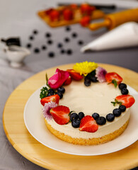 Sweet cheesecake decorated with fresh berry fruits, and flowers on a wooden plate, for birthday, Valentine day and celebration