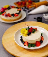 Sweet cheesecake decorated with fresh berry fruits, and flowers on a wooden plate , for birthday, Valentine day and celebration