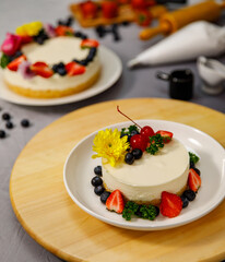 Sweet cheesecake decorated with fresh berry fruits, and flowers on a wooden plate , for birthday, Valentine day and celebration