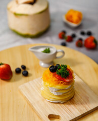 Crepe cake with coconut milk sauce delicious decorated with golden egg yolk threads on a wooden plate