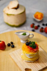 Crepe cake with coconut milk sauce delicious decorated with golden egg yolk threads on a wooden plate