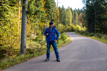 Man with a backpack stay on a forest road
