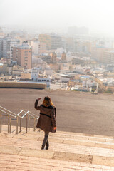 A young tourist on the stairs of the viewpoint of Cerro San Cristobal and the city of Almeria in the background, Andalucia. Spain. Costa del sol in the mediterranean sea