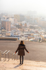 A young tourist on the stairs of the viewpoint of Cerro San Cristobal and the city of Almeria in the background, Andalucia. Spain. Costa del sol in the mediterranean sea, vertical photo