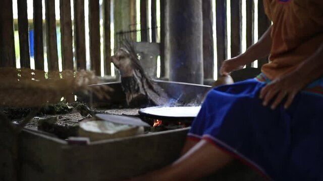 Indigenous woman of the siona culture in Ecuador is making bread from yuca on a clay pan
