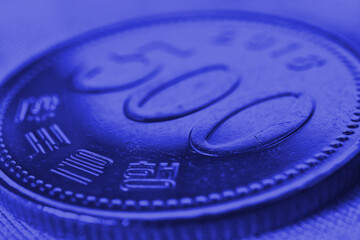 Translation: Bank of Korea. 500 won coin close-up. Dark blue tinted background or wallpaper on an economic, financial or banking theme. Money and business in South Korea. Korean won. Macro