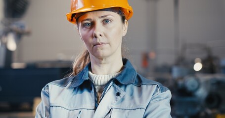 Portrait of a professional engineer - heavy industry worker in protective uniform and helmet. In the background, a large industrial plant