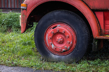 Grosse roue d'un vieux camion rouge ancien, roue vintage avec écrous