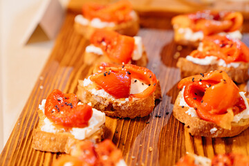 canapes. small sandwiches with cheese and dried vegetables on a wooden tray. Catering. delicious and simple snacks for the banquet.