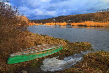 Rural autumn landscape with boat and river.