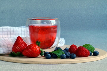 on a tray there is a beautiful berry jelly in a transparent glass and fresh berries lie