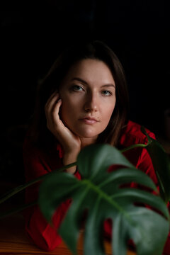 Portrait of a beautiful woman in red dress with a monstera leaf