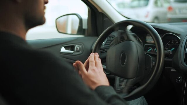 Man driving in innovative automated car using self-parking autopilot for parking on parking lot. Rear view from behind the driver's shoulder