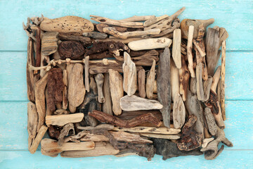 Driftwood art nature sculpture on rustic blue background with large collection of natural weathered wooden pieces. Natural creative design. Flat lay top view.