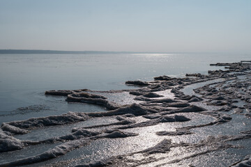 Landscape of a frozen lake, ice, water with blue sky on horizon. Winter cold climate