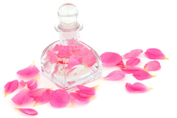 Rose water in an art deco glass bottle and pink petals. Can help maintain skin pH balance, is anti bacterial, helps to reduce redness of skin, can help heal acne, dermatitis and eczema. On white.