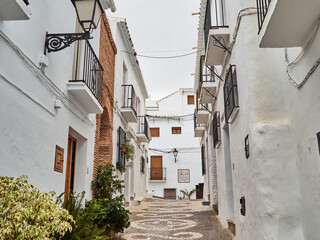 Fototapeta na wymiar Typical street of Frigiliana, a small white village with cobblestone streets in the Axarquía region of the Costa del Sol, Málaga province, Andalusia, Spain. Europe