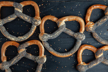 Fresh prepared homemade soft pretzels. Different types of baked bagels with seeds on a black background