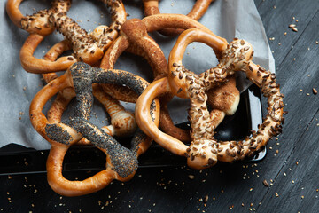 Fresh prepared homemade soft pretzels. Different types of baked bagels with seeds on a black background.
