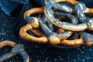 Fresh prepared homemade soft pretzels. Different types of baked bagels with seeds on a black background.