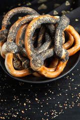 Fresh prepared homemade soft pretzels. Different types of baked bagels with seeds on a black background.