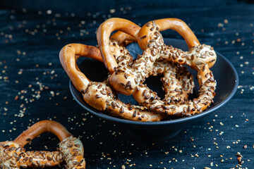 Fresh prepared homemade soft pretzels. Different types of baked bagels with seeds on a black background.