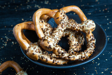 Fresh prepared homemade soft pretzels. Different types of baked bagels with seeds on a black background.