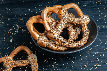 Fresh prepared homemade soft pretzels. Different types of baked bagels with seeds on a black background.