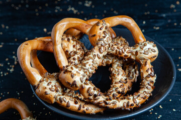Fresh prepared homemade soft pretzels. Different types of baked bagels with seeds on a black background.