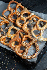 Fresh prepared homemade soft pretzels. Different types of baked bagels with seeds on a black background.