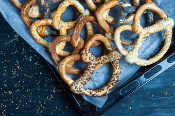 Fresh prepared homemade soft pretzels. Different types of baked bagels with seeds on a black background.