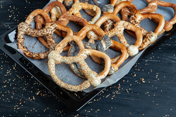 Fresh prepared homemade soft pretzels. Different types of baked bagels with seeds on a black background.